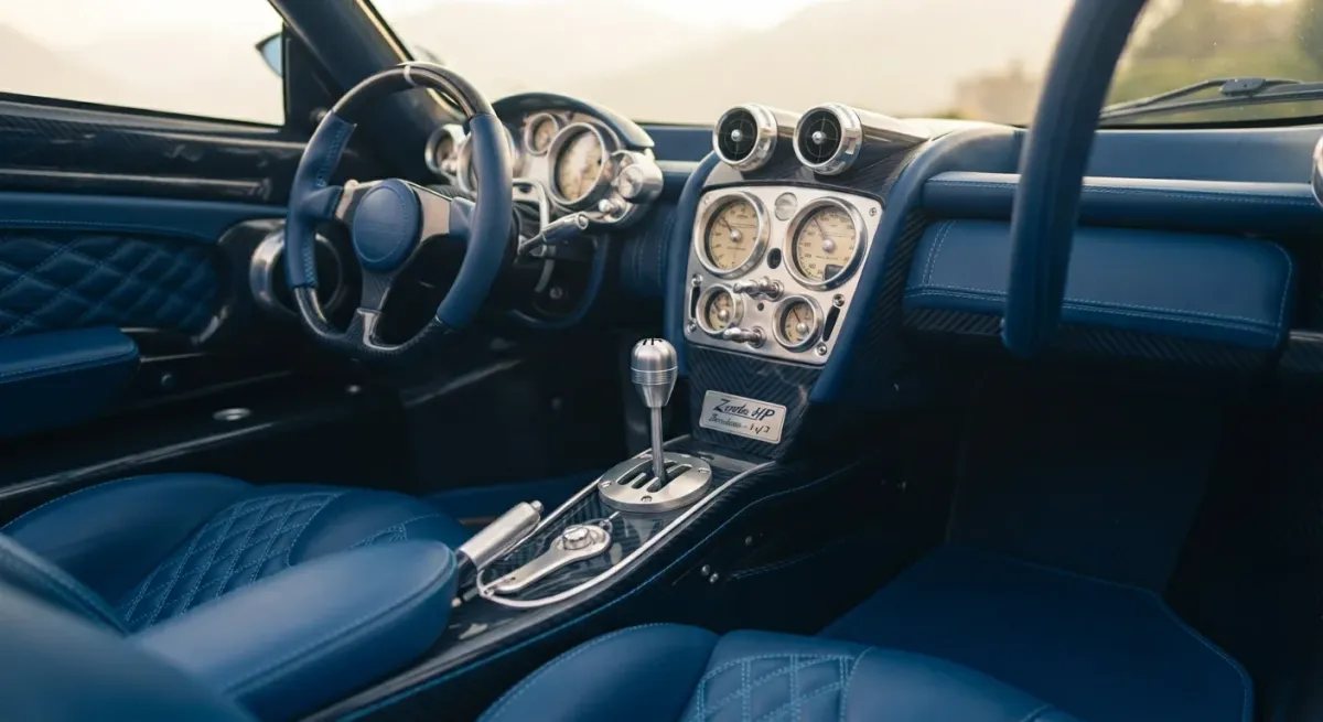 Detalle del interior artesanal del Pagani Zonda HP Barchetta, con tapicería azul, detalles de aluminio y cambio manual visible.