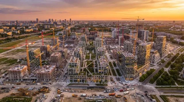 Vista aérea de múltiples grúas de construcción y edificios residenciales nuevos al atardecer, simbolizando el aumento masivo de la oferta de vivienda.