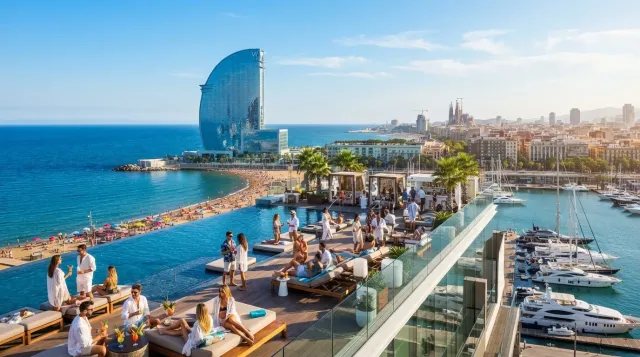 Vista panorámica del Hotel W Barcelona, su piscina infinita y la playa de la Barceloneta con yates de lujo.