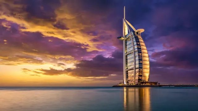 El Burj Al Arab de Dubái iluminado al atardecer frente al golfo Pérsico, símbolo mundial de la hostelería de ultra-lujo.