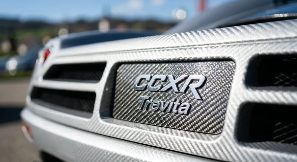 Primer plano macro hiperrealista de la insignia trasera y la intrincada textura de fibra de carbono plateada visible del Koenigsegg CCXR Trevita.